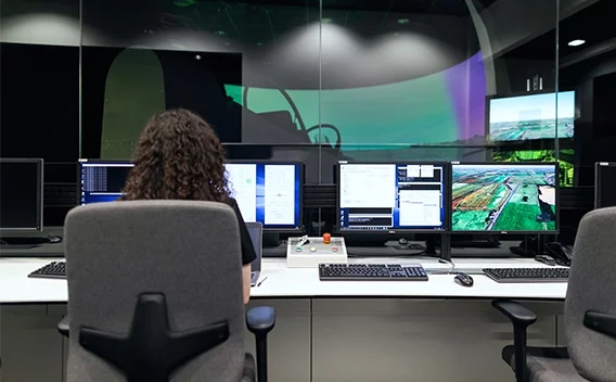 Woman sitting in an office chair looking at several computer monitors