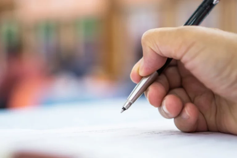 Hand holding pen writing on paper